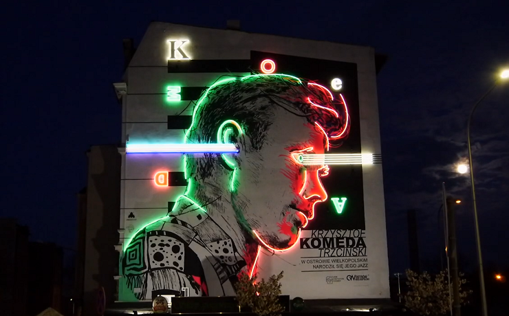  Mural z wizerunkiem Krzysztofa Komedy rozświetlony neonem